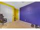 Bedroom with bright yellow and purple walls, and a gaming chair at 40657 W Somers Dr, Maricopa, AZ 85138