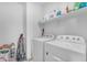 Bright laundry room features washer, dryer, and storage shelves at 40657 W Somers Dr, Maricopa, AZ 85138