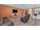 Modern living room featuring orange accent wall, TV, and wood-style flooring at 40657 W Somers Dr, Maricopa, AZ 85138