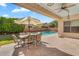 Backyard patio with dining set offering views of a sparkling pool with water features and manicured landscaping at 4236 S John Way, Chandler, AZ 85249