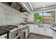 Gourmet kitchen featuring stainless steel appliances, white cabinets, and stylish tile backsplash at 438 E Larkspur Ln, Tempe, AZ 85288