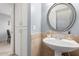 A powder room features a round mirror, pedestal sink, beige tile, and a white cabinet at 4600 N 68Th St # 379, Scottsdale, AZ 85251
