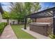 View of hot tub under a pergola with artificial grass, stone pavers, and surrounding greenery at 4711 E Buckboard Ct, Gilbert, AZ 85297
