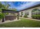 Backyard showcasing a hot tub beneath a pergola and the exterior of the home with arched windows at 4711 E Buckboard Ct, Gilbert, AZ 85297