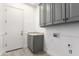 Laundry room with grey shaker cabinets, granite counters, sink, and door to outside at 4711 E Buckboard Ct, Gilbert, AZ 85297