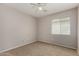 This carpeted bedroom has a ceiling fan and a large window at 5320 E Silverbell Rd, San Tan Valley, AZ 85143