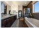 Spa-like bathroom with a soaking tub, dual vanities, dark wood accents, and modern fixtures, offering a luxurious experience at 7432 W Bronco Trl, Peoria, AZ 85383