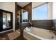 Bright bathroom features a soaking tub with decorative tile surround, window, and glass shower at 7432 W Bronco Trl, Peoria, AZ 85383