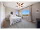 Bright bedroom features a large window with scenic views, neutral walls and carpet, and a ceiling fan at 7432 W Bronco Trl, Peoria, AZ 85383