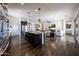 Open-concept kitchen featuring a large island, stainless steel appliances, and dark wood floors, seamlessly flowing into the living area at 7432 W Bronco Trl, Peoria, AZ 85383