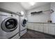 Well-organized laundry room with modern washer and dryer, plenty of cabinet space, and tile floor at 7432 W Bronco Trl, Peoria, AZ 85383