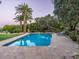 Beautiful swimming pool with brick coping, surrounded by lush greenery and swaying palm trees at 8022 N Ironwood Dr, Paradise Valley, AZ 85253