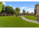 Expansive backyard featuring lush green lawn, brick walkway, pergola, pool, and mature landscaping at 10033 W Jessie Ln, Peoria, AZ 85383