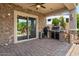 Outdoor kitchen on a covered patio with ceiling fan, stone accents, a large sliding glass door and brick flooring at 10033 W Jessie Ln, Peoria, AZ 85383