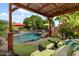 Inviting covered pergola with comfortable seating, overlooking a backyard pool and lush landscaping at 10033 W Jessie Ln, Peoria, AZ 85383
