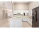 Open kitchen area featuring white cabinetry, an island, and stainless steel refrigerator at 11524 W Rosewood Dr, Avondale, AZ 85392