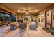 Inviting covered patio with travertine flooring and wicker seating, perfect for outdoor relaxation and entertainment at 13252 W Steed Ridge Rd, Peoria, AZ 85383