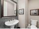 Stylish powder room with a decorative mirror, pedestal sink, and tiled accent wall at 13252 W Steed Ridge Rd, Peoria, AZ 85383
