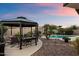 Lush backyard oasis featuring a charming gazebo, a sparkling pool, and mature landscaping under a colorful sky at 13634 W San Miguel Ave, Litchfield Park, AZ 85340
