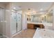 Well-lit bathroom with a walk-in shower, large vanity mirror, and a soaking tub for relaxation at 13634 W San Miguel Ave, Litchfield Park, AZ 85340