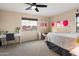 Bright bedroom with a white desk, a comfy chair, and modern wall art, illuminated by natural light at 13634 W San Miguel Ave, Litchfield Park, AZ 85340