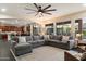 Spacious living room with large windows, a ceiling fan, and a comfortable sectional couch overlooking a manicured backyard at 13634 W San Miguel Ave, Litchfield Park, AZ 85340