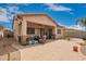 Spacious backyard featuring a covered patio, desert landscaping, and brick pavers at 1410 W Popcorn Tree Ave, Queen Creek, AZ 85140