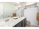 Well-lit bathroom featuring a double vanity, ample counter space, and a shower with a white curtain at 181 N 222Nd Dr, Buckeye, AZ 85326