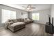 Bright living room with wood floors, a large sectional sofa, and natural light from two windows at 181 N 222Nd Dr, Buckeye, AZ 85326