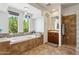 Bathroom featuring a tub with tile surround, pendant lights and a window with a view of trees at 18329 W Montebello Ave, Litchfield Park, AZ 85340