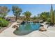 Sparkling private pool with rock waterfall, lush landscaping, and desert vegetation at 18329 W Montebello Ave, Litchfield Park, AZ 85340