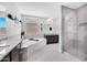Open bathroom featuring a soaking tub, glass shower, and dual dark wood vanities at 18493 W Hiddenview Dr, Goodyear, AZ 85338