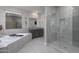 Bathroom featuring a soaking tub, large shower, gray tile, and large mirror at 18493 W Hiddenview Dr, Goodyear, AZ 85338