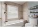 Neutral bathroom with a tiled shower-tub, window, and tiered storage at 19 W Wickieup Ln, Phoenix, AZ 85027