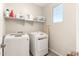 Bright laundry room with a front-loading washer and dryer set, and shelving for organized storage at 22962 N 182Nd Ln, Surprise, AZ 85387