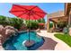 Refreshing pool featuring a central umbrella stand, complemented by lush landscaping and rock waterfall feature at 241 W Roadrunner Dr, Chandler, AZ 85286