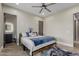 Bright bedroom featuring a modern ceiling fan, neutral walls, wood-look tile flooring, and an ensuite bathroom at 2516 W Joy Ranch Rd, Phoenix, AZ 85086