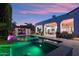 Beautiful backyard with a sparkling pool, pergola with dining, and lush landscaping at dusk at 2748 E Warbler Rd, Gilbert, AZ 85297