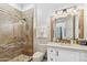 Well-lit bathroom featuring a tiled shower, a toilet, and a vanity with an eye-catching mirror at 2748 E Warbler Rd, Gilbert, AZ 85297