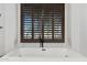Modern bathtub with custom wooden blinds and matte black fixtures at 2748 E Warbler Rd, Gilbert, AZ 85297