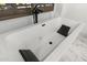 Close up of modern soaking tub with black matte fixtures and tile surround at 2748 E Warbler Rd, Gilbert, AZ 85297