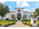 Elegant stucco home with manicured lawn, illuminated walkway, and decorative wrought iron gate at 2748 E Warbler Rd, Gilbert, AZ 85297