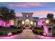 Elegant stucco home with manicured lawn, illuminated walkway, and decorative wrought iron gate in the evening at 2748 E Warbler Rd, Gilbert, AZ 85297