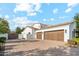 Elegant home featuring a three-car garage and a brick-paved driveway, creating a luxurious and welcoming entrance at 2748 E Warbler Rd, Gilbert, AZ 85297
