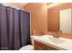 Orange toned bathroom featuring a vanity, toilet, faucet and dark shower curtain at 3410 W Pershing Ave, Phoenix, AZ 85029