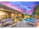 Beautiful backyard with a sparkling pool, covered patio, and outdoor seating at dusk at 3523 W Buckhorn Trl, Phoenix, AZ 85083