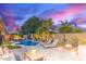 Inviting pool with lounge chairs, umbrellas, green plants, and outdoor seating at dusk at 3523 W Buckhorn Trl, Phoenix, AZ 85083