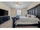This cozy bedroom features neutral walls, a ceiling fan, and a modern entertainment center at 36412 W Pampoloma Ave, Maricopa, AZ 85138