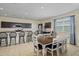 Open-concept kitchen and dining area with stylish dark cabinets, island seating and tiled flooring at 36412 W Pampoloma Ave, Maricopa, AZ 85138