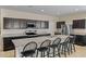 Stylish kitchen featuring dark cabinets, granite countertops, and a spacious island with seating at 36412 W Pampoloma Ave, Maricopa, AZ 85138
